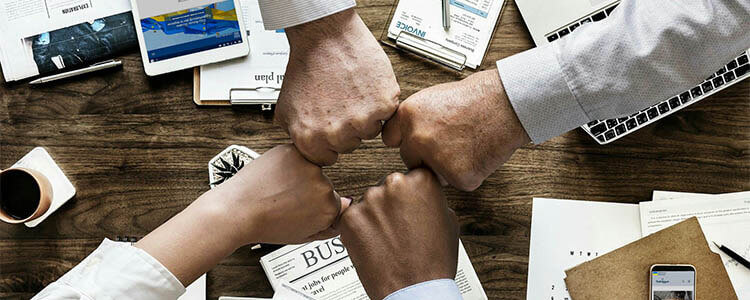 quattro mani che si toccano facendo il pugno in segno di team work