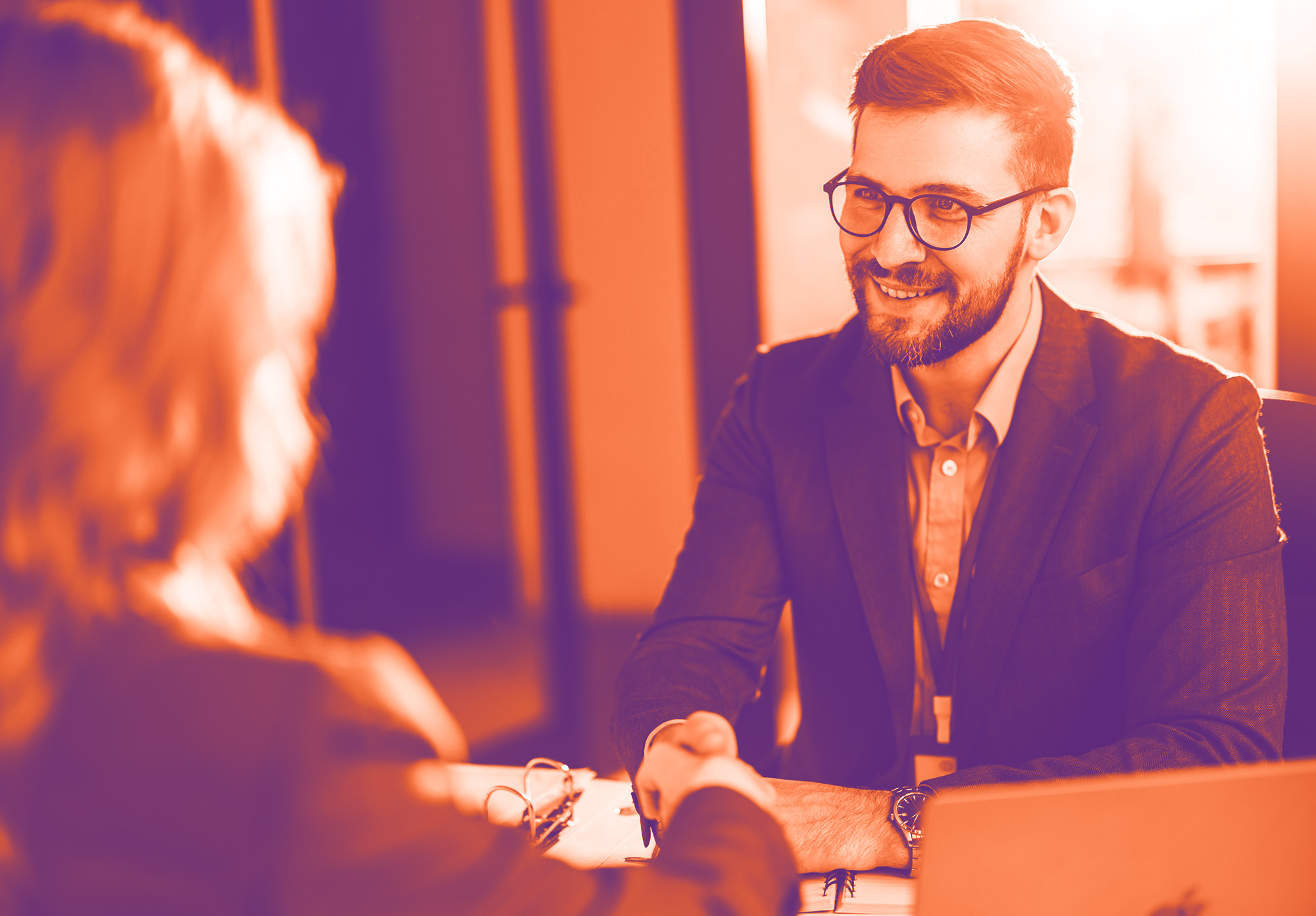 foto con gradiente arancione e viola che ritrae una donna di spalle e un uomo davanti che le stringe la mano e sorride