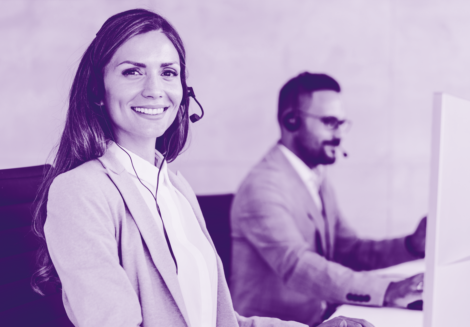 foto con gradiente viola dove ci sono due persone al centralino che rispondono al telefono con delle cuffie, la donna davanti in primo piano sorride, l'uomo sullo sfondo è sfuocato e guarda il pc