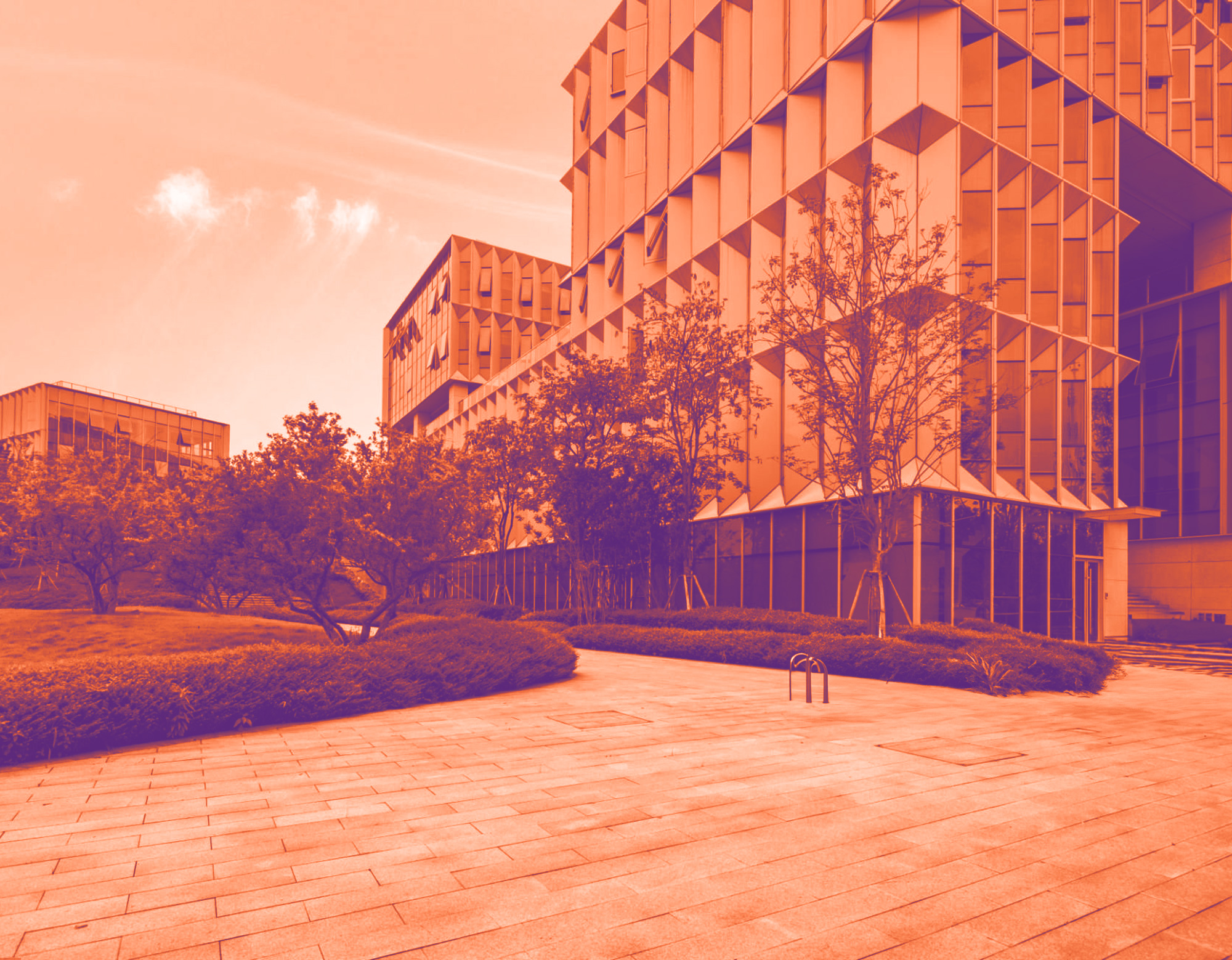 foto con gradiente arancione con una grande azienda e davanti con parco con degli alberi per rappresentare le grandi imprese