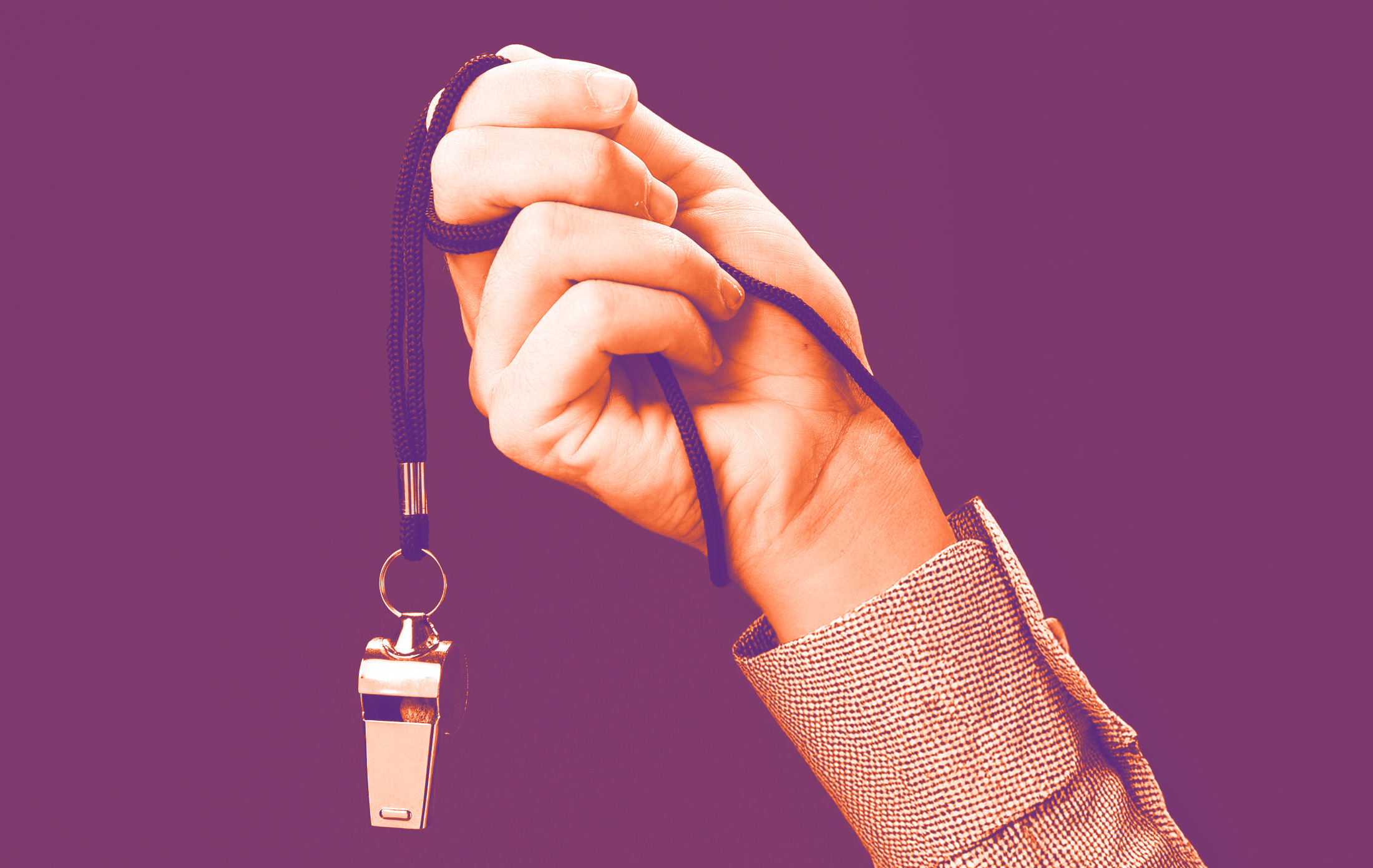 foto con sfondo viola e un braccio che tiene in mano un fischietto sui tone dell'arancione