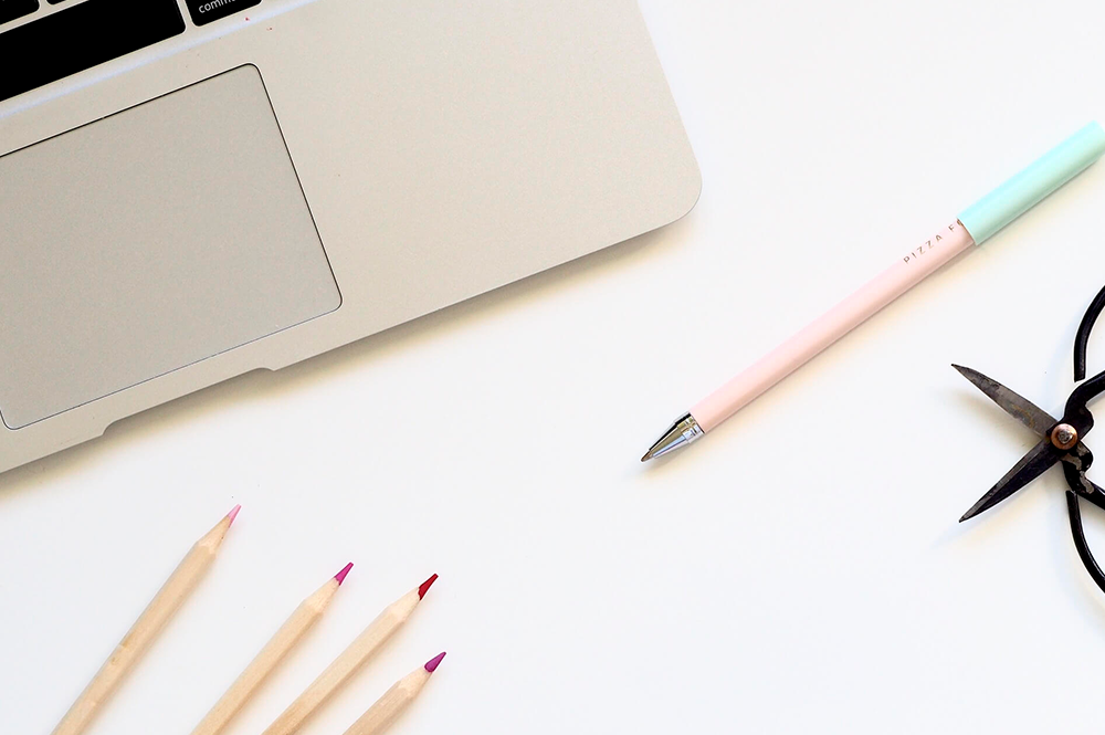 su una scrivania c'è un pezzo di pc e matite colorate