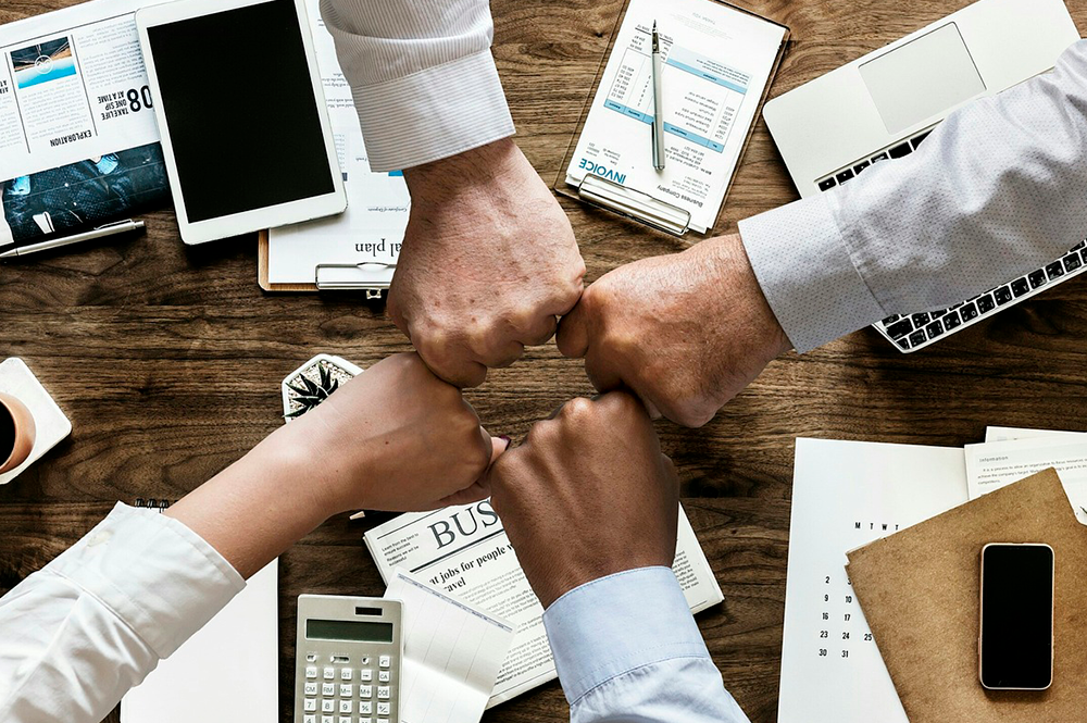 quattro mani che si toccano facendo il pugno in segno di team work