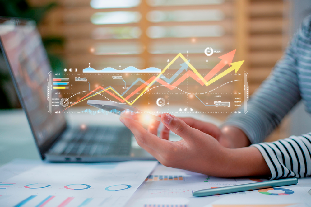 pc sullo sfondo, telefono sulle mani con disegni di grafici sopra