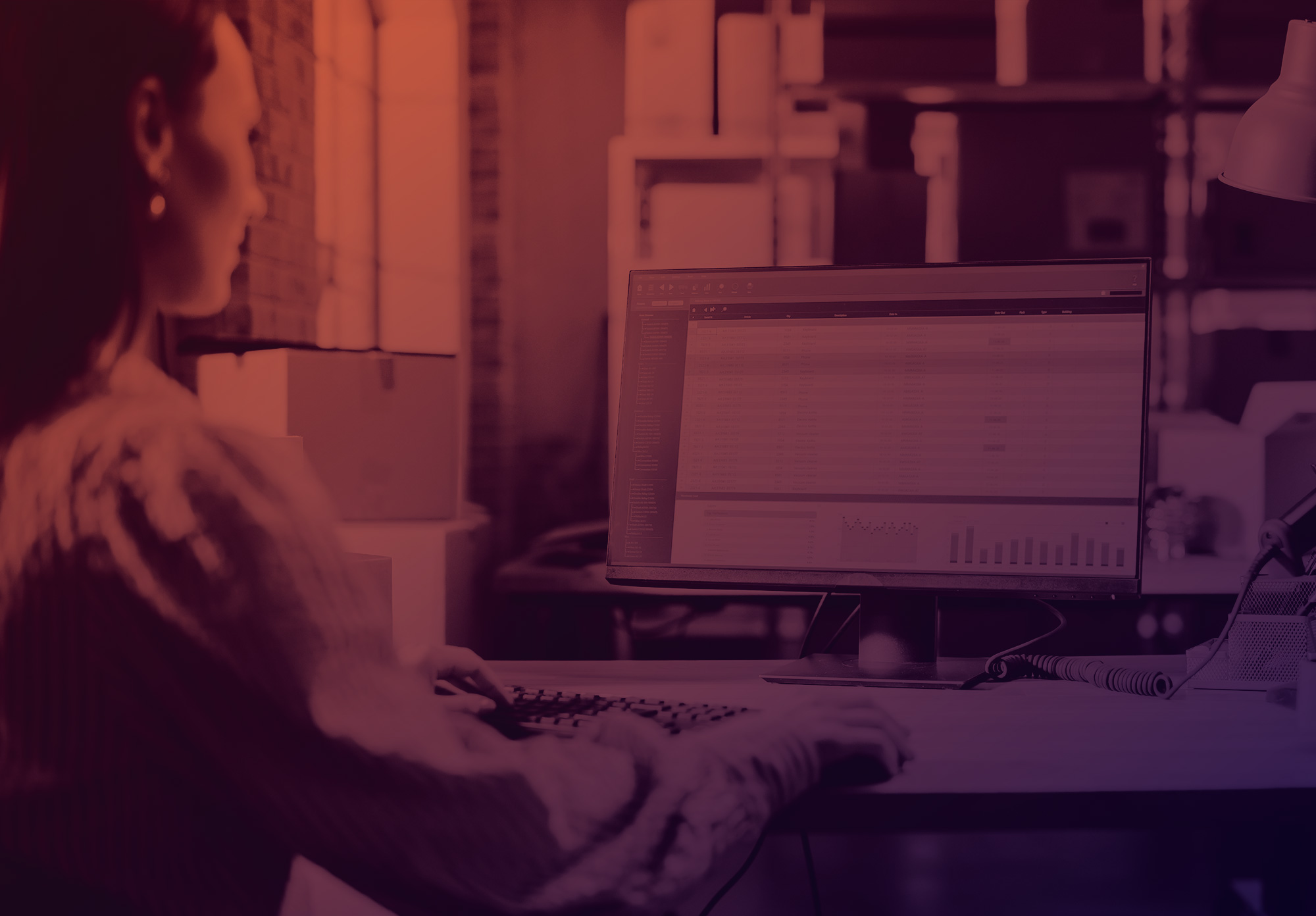 foto con gradiente scuro sull'arancione e viola. Sulla sinistra si vede una donna con i capelli lunghi di spalle che lavora al pc 