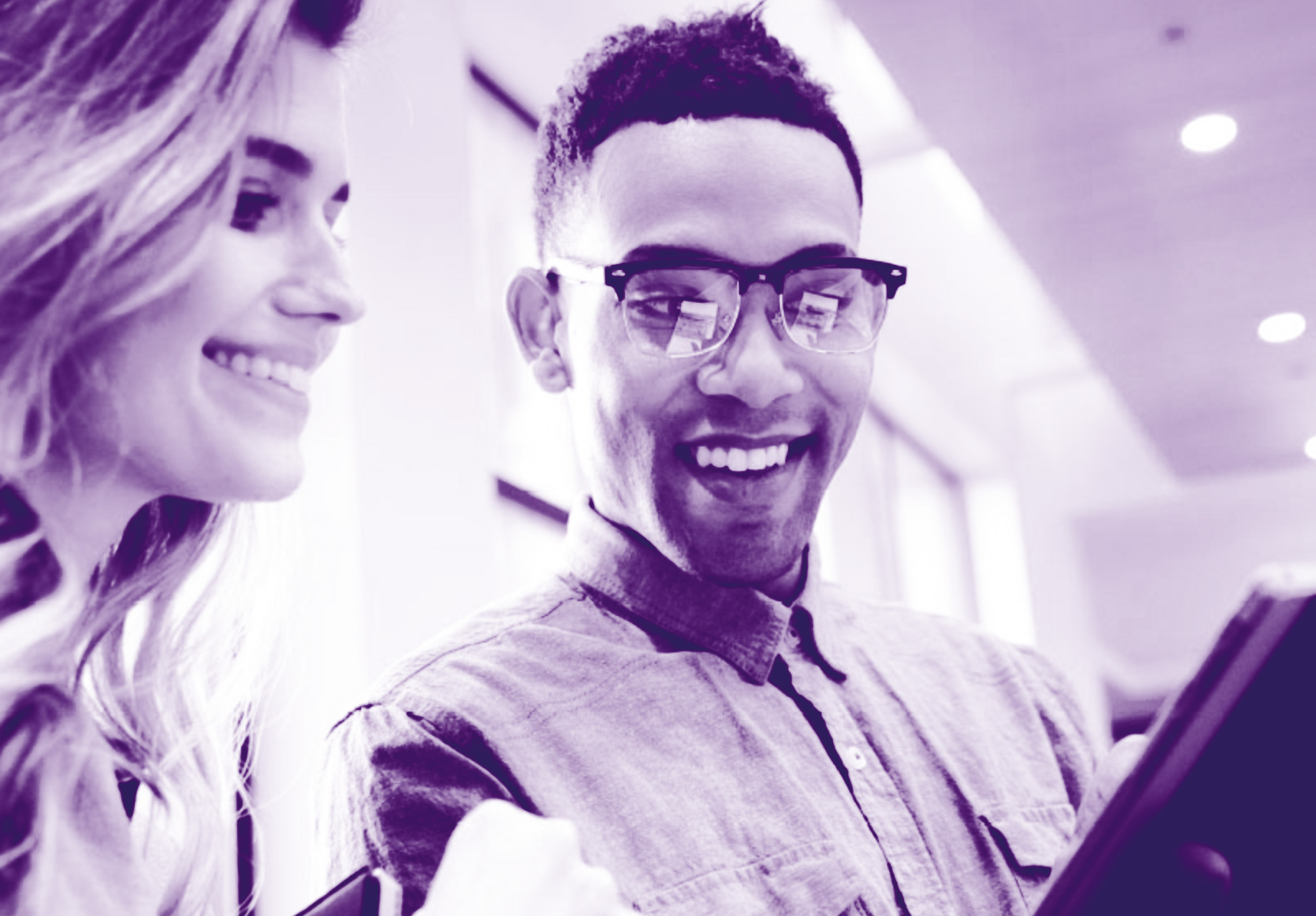 Foto con gradiente viola con due ragazzi che guardano un tablet e sorridono